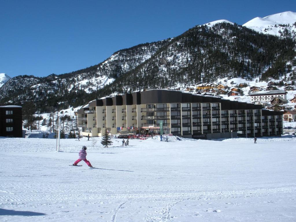una niñita esquiando en la nieve frente a un hotel en Studio a Montgenevre a 400 m des pistes avec balcon et wifi, en Montgenèvre