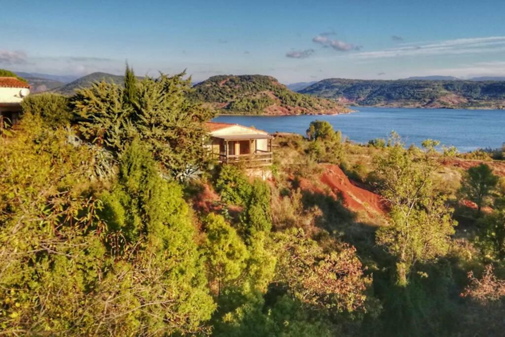 ein Haus auf einem Hügel neben einem Wasserkörper in der Unterkunft Studio 32m2 - dans propriété avec vue imprenable sur le Lac du Salagou in Liausson