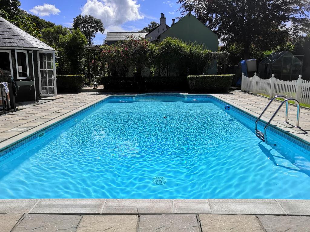 a swimming pool with blue water in a yard at Captivating Isolde Cottage with pool near St Ives in Camborne