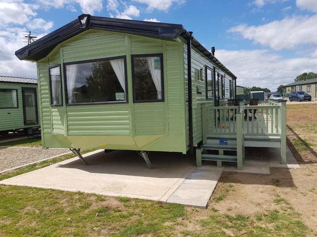 a green tiny house sitting on the grass at Stunning 6 Birth Caravan in Skegness Herons Mead in Orby