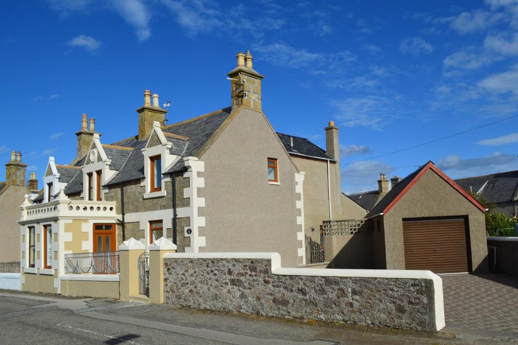 ein großes Haus mit einem Zaun davor in der Unterkunft The View 3-Bed Cottage Findochty Buckie Moray in Findochty