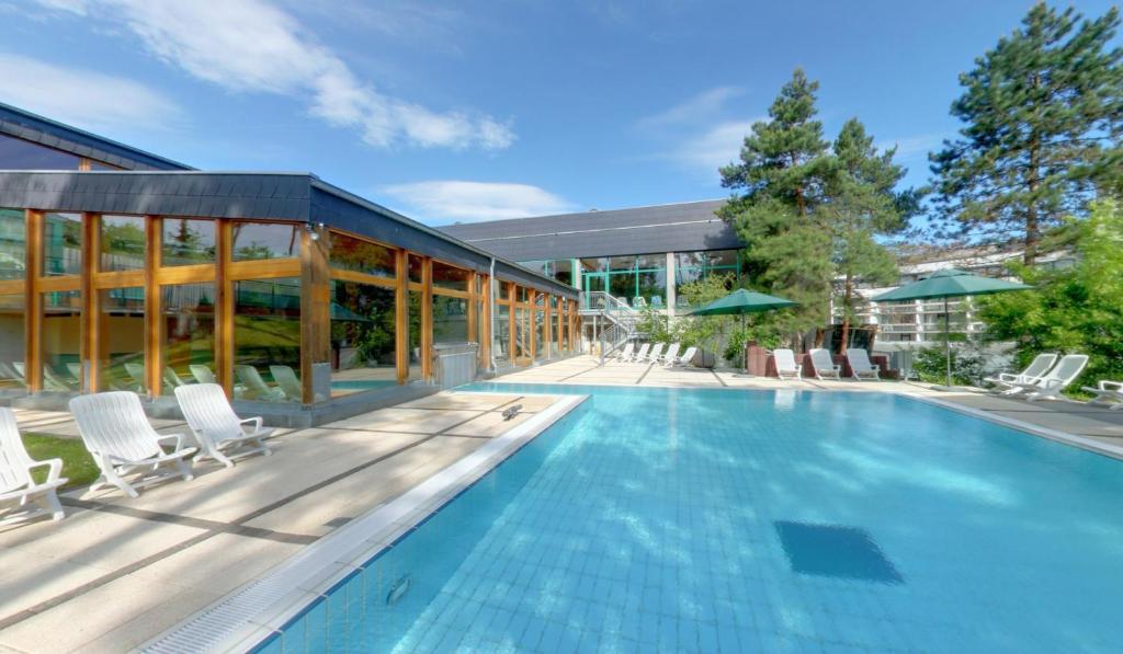 une piscine avec des chaises et un bâtiment dans l'établissement Hotel Sonnenhügel, à Bad Kissingen