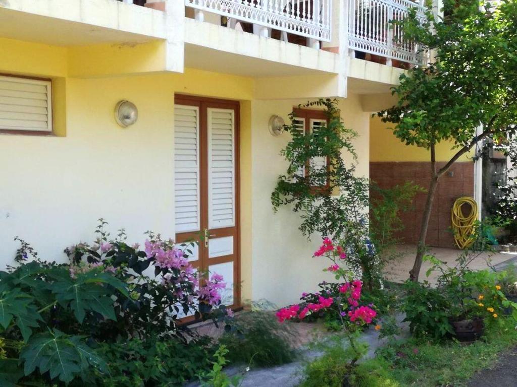 una casa con balcón y flores delante de ella en Maison de 2 chambres avec vue sur la mer terrasse amenagee et wifi a Les Anses d'Arlet, en Les Anses-dʼArlet