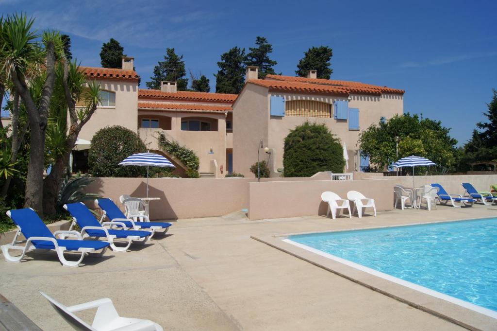 un complejo con piscina, sillas y una casa en L'Orangeraie Claira 66 en Claira