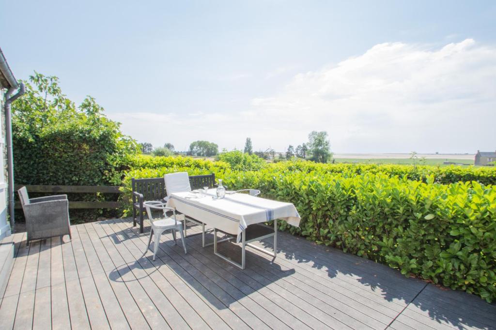 a white table and chairs on a patio with a vineyard at Maison de 3 chambres avec vue sur la mer jardin clos et wifi a Regneville sur Mer a 2 km de la plage in Regnéville-sur-Mer