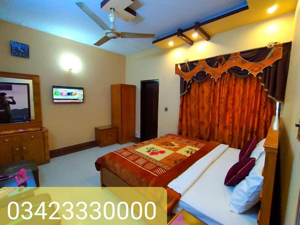 a bedroom with a bed and a flat screen tv at Royal Residency Guest House Karachi in Karachi