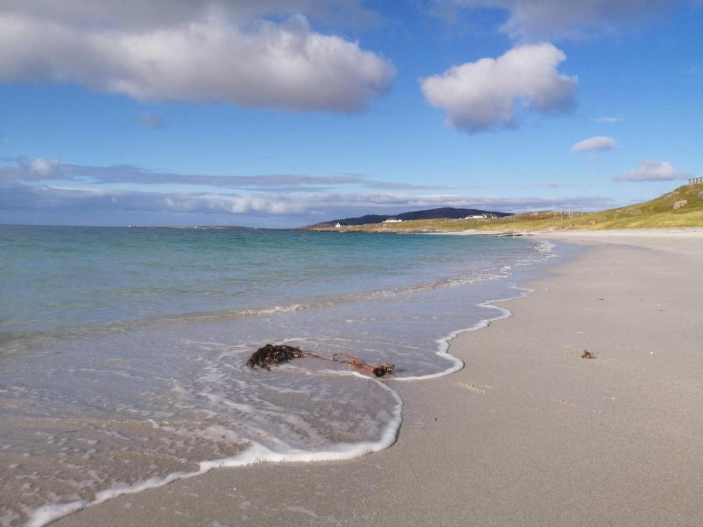 a person laying in the water on a beach at Glamping Pod for 2 Pod Beag Na Haun Eriskay in Eriskay