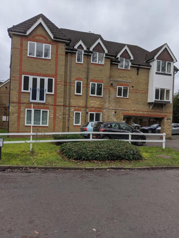 una grande casa di mattoni con una recinzione bianca di fronte di Oaklawn serviced apartments a Woking