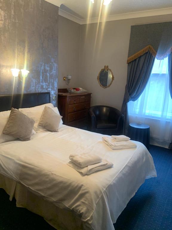 Un dormitorio con una cama blanca con toallas. en The Beckett Guest House, en York