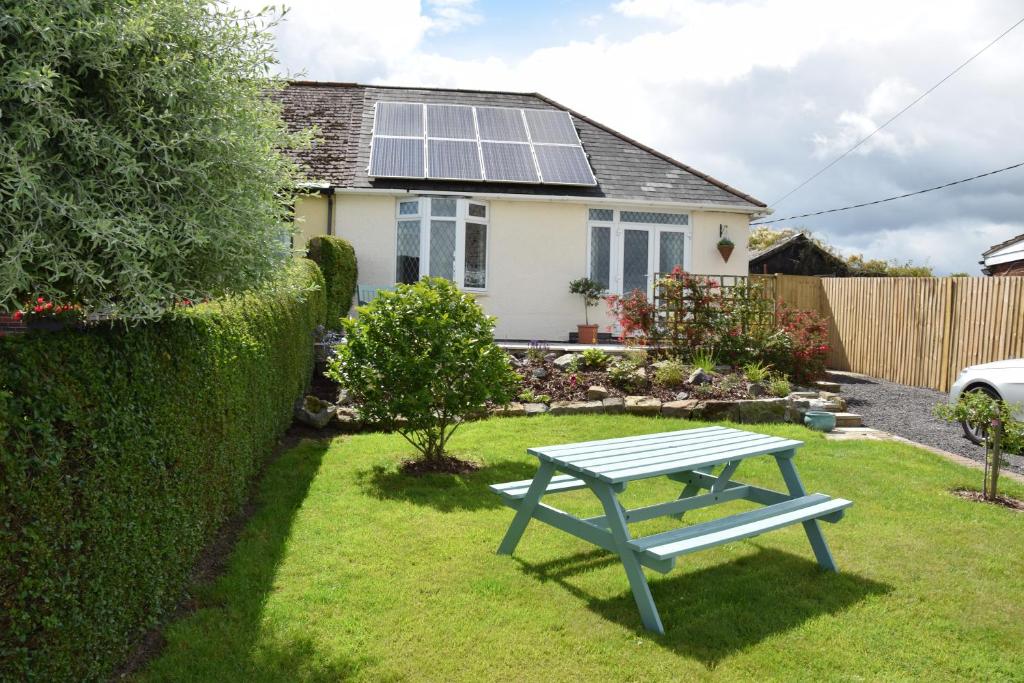 una mesa de picnic azul frente a una casa con techo solar en Immaculate Inviting light and airy 2-Bed Cottage, en Tibshelf