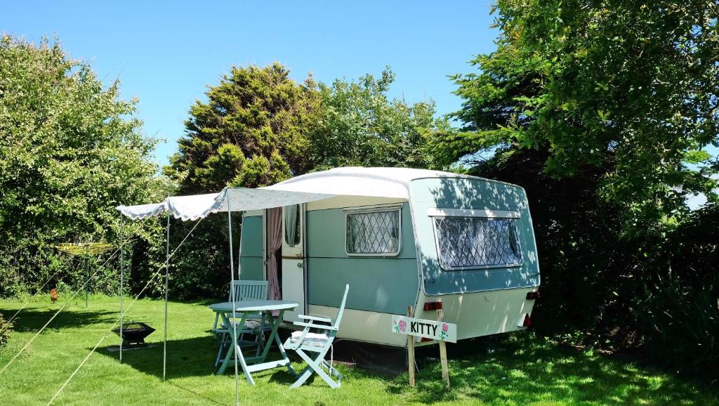 une caravane verte avec une table et une tente dans l'établissement KItty unique 60s caravan set in pretty garden, à Lizard