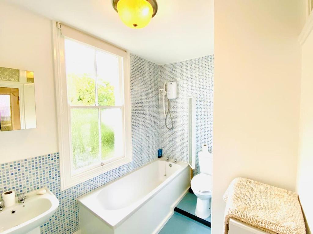 a bathroom with a tub and a sink and a toilet at Beachfront Retreat With Panoramic Views Of The Bay in Whitstable
