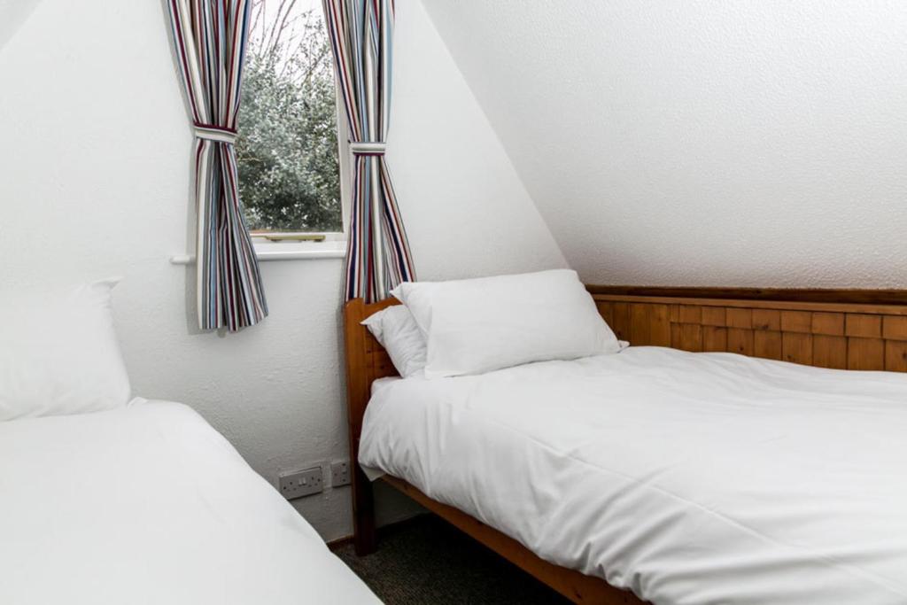 two beds in a small room with a window at Seaside Chalet - Sleeps 6 in Kingsdown