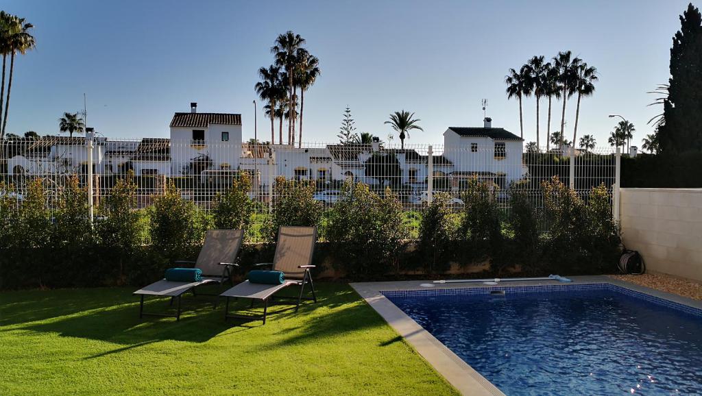 a yard with two chairs and a swimming pool at Casa Blanco - Luxury Detached Villa in San Javier