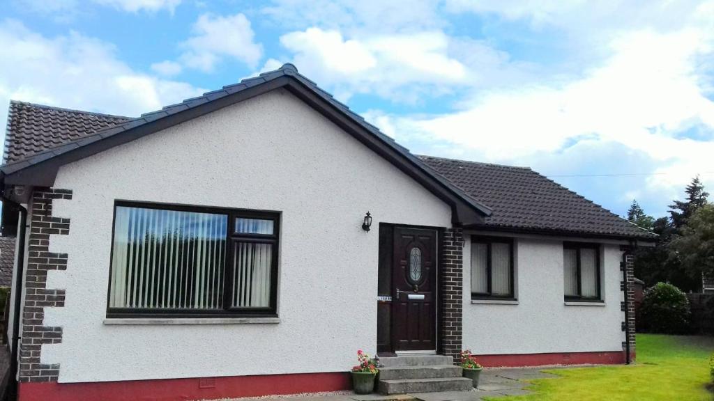 a white house with a brown door at 2 Bed home with private garden in the Highlands in Beauly