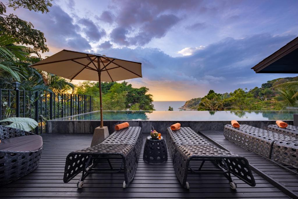 Villa Yang, Private Oceanfront Villa, Kamala Beach في شاطئ كامالا: سطح خشبي مع طاولتين ومظلة