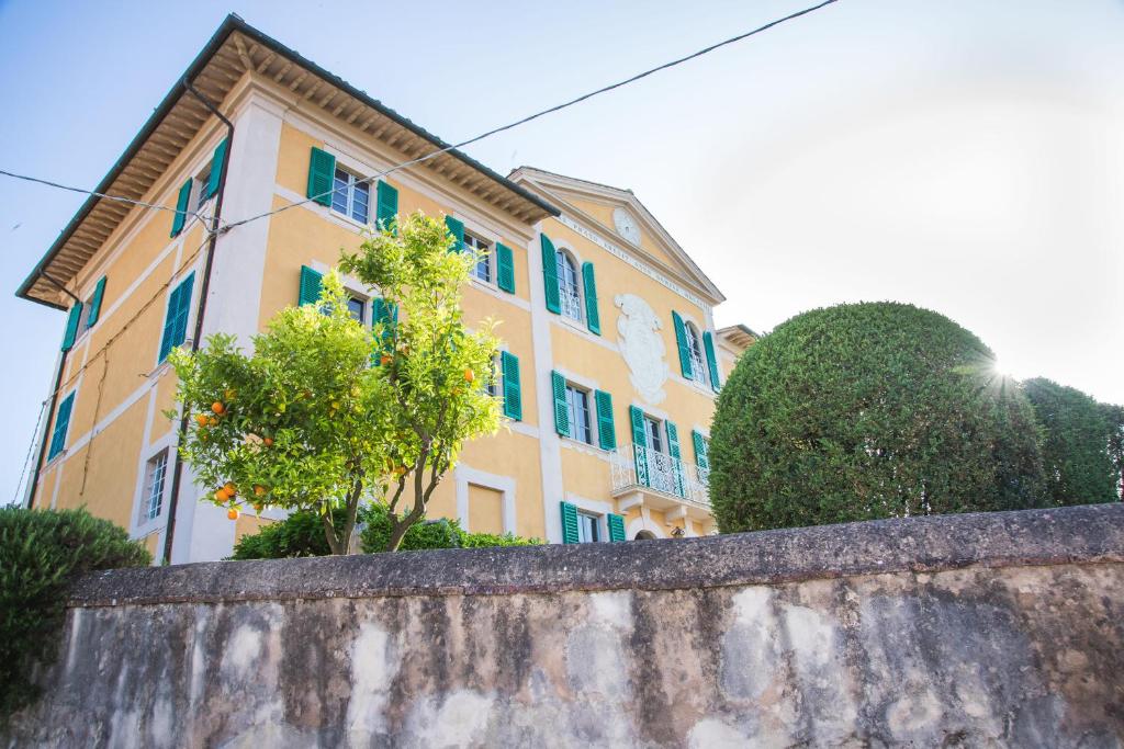 カシャーナ・テルメにあるVilla Prato-Lamiの青窓と木が特徴の大きな黄色の建物
