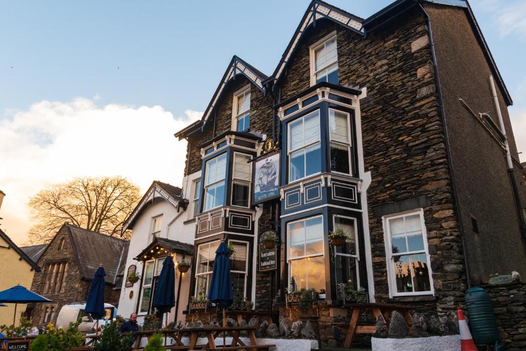 ein großes Steinhaus mit blauen Sonnenschirmen davor in der Unterkunft The Royal Oak Inn in Bowness-on-Windermere