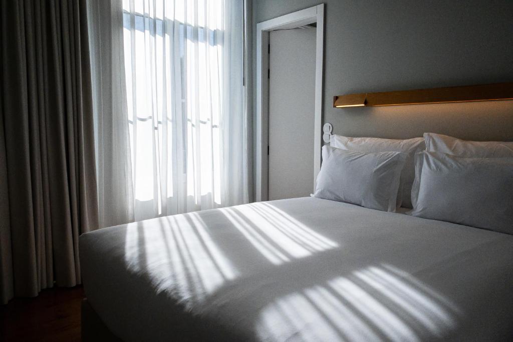 a bedroom with a large white bed with a window at A House in Estoril - Adults Only in Estoril
