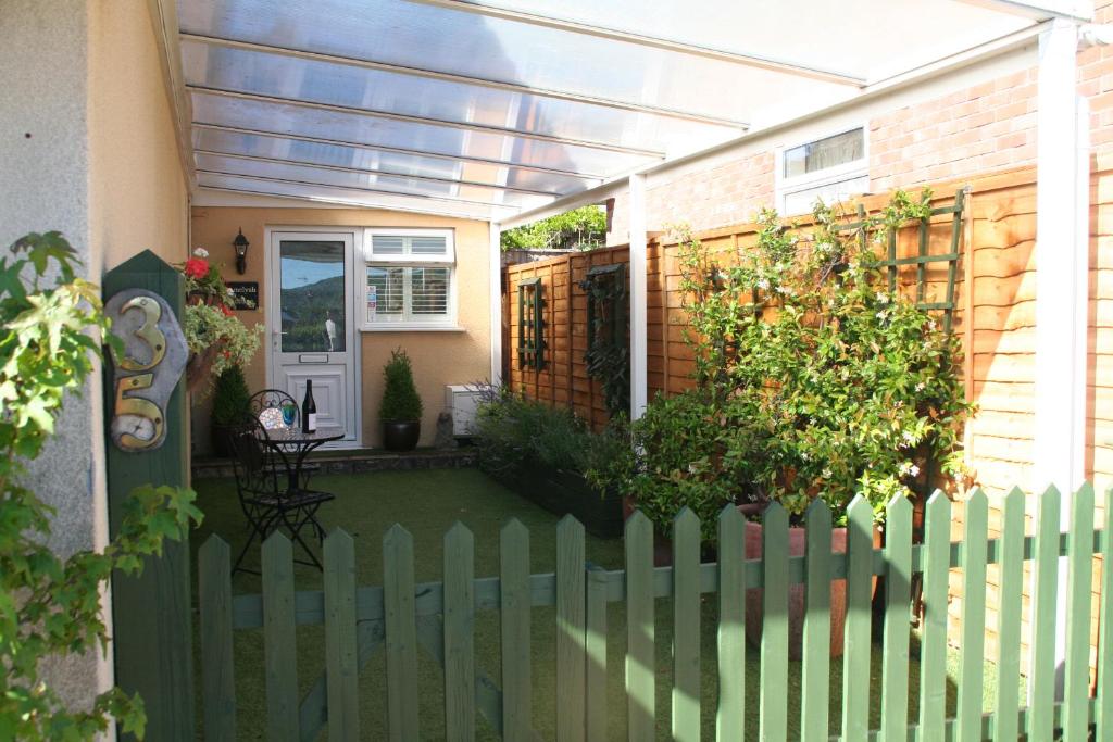 a green fence in front of a house at Amelyah Studio Cottage in Beautiful Countryside in Winscombe