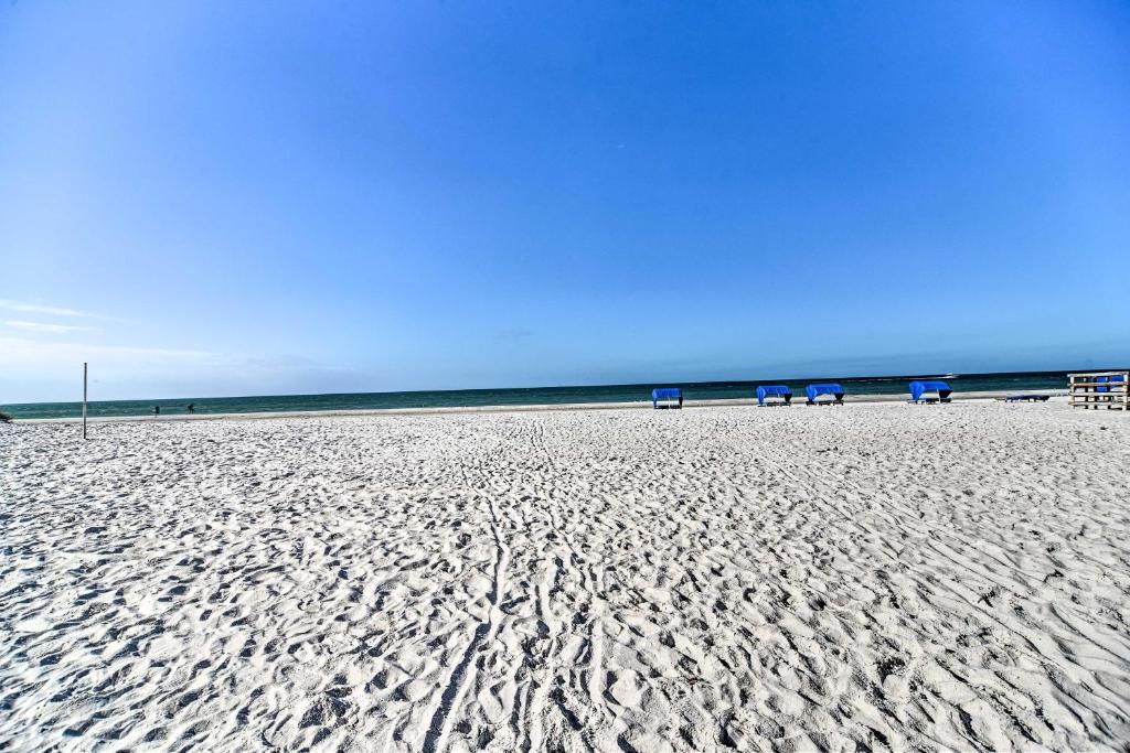 a beach with chairs and the ocean in the background at Beachfront Indian Shores Condo - Pool and Hot Tub! in Clearwater Beach