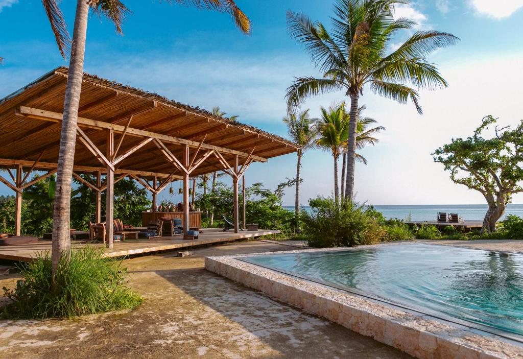 a resort pool with a pavilion and palm trees at Kizikula in Kizimkazi