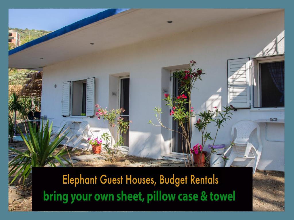 a white house with a sign in front of it at Elephant Guest Houses in Évdhilos