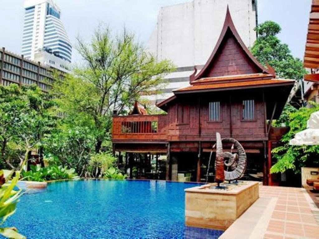 a building with a house next to a swimming pool at Rose Hotel in Bangkok
