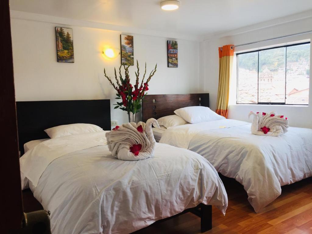 a bedroom with two beds with white sheets and a window at Hospedaje Qori Punku in Cusco