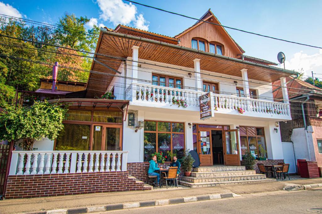 a woman sitting at a table in front of a building at Casa Albă in Baia de Aramă