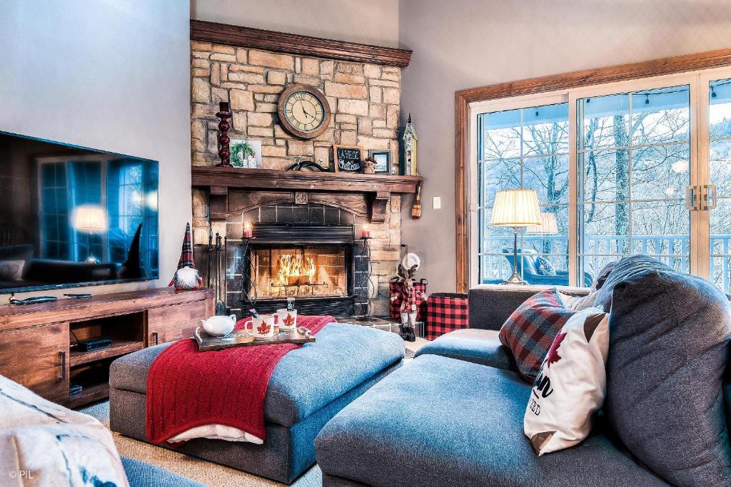 Una sala de estar con un sofá y una chimenea. en Les Manoirs 3bdrs W Pool & Hottub Near Village, en Mont-Tremblant