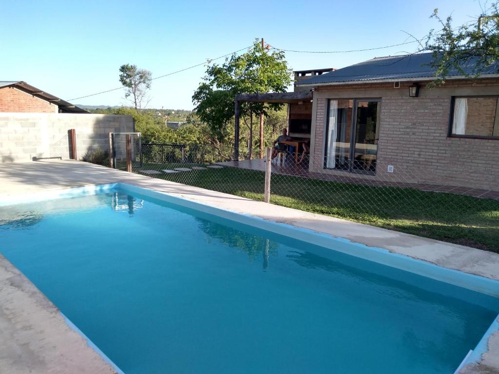 a large blue swimming pool in front of a house at Cabañas Quimera in Santa Rosa de Calamuchita