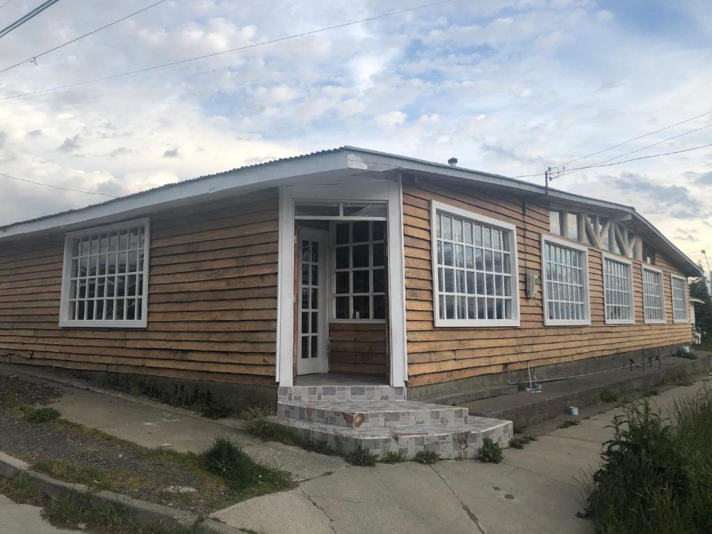 Casa de madera pequeña con puerta y ventanas en El Sendero, en Puerto Natales