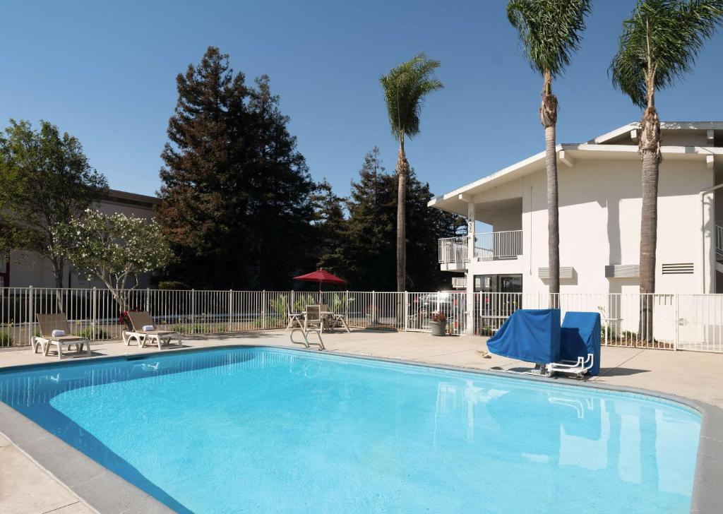 una piscina con 2 sillas y una casa en Motel 6-San Luis Obispo, CA - North, en San Luis Obispo