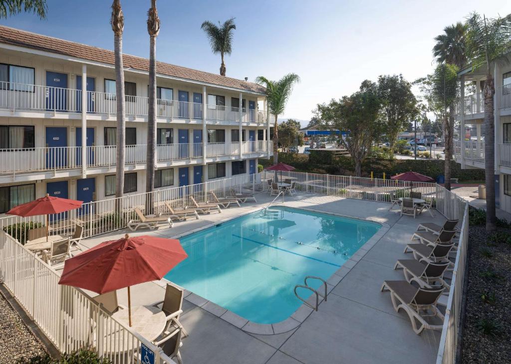 a swimming pool in front of a hotel with chairs and umbrellas at Motel 6-Carpinteria, CA - Santa Barbara - North in Carpinteria
