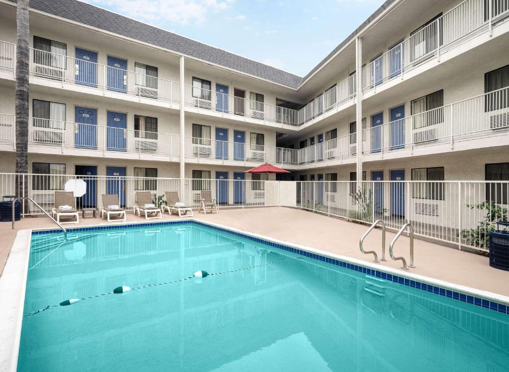 a swimming pool in front of a building with a hotel at Motel 6-Buena Park, CA - Knotts Berry Farm - Disneyland in Buena Park