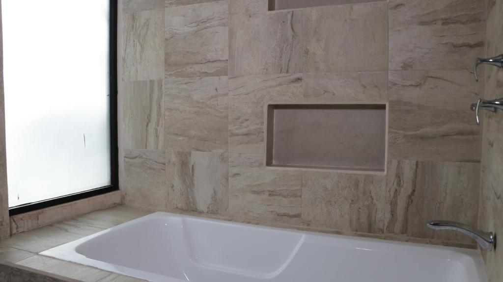 a bath tub in a bathroom with a stone wall at Hotel Itza Coba in Cobá