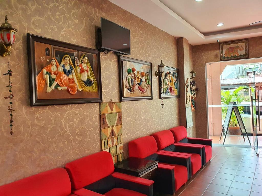 a waiting room with red chairs and paintings on the wall at Little India Heritage Villa in George Town