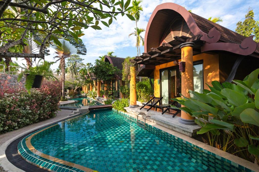a villa with a swimming pool in front of a house at The Village Resort & Spa - SHA Plus in Karon Beach