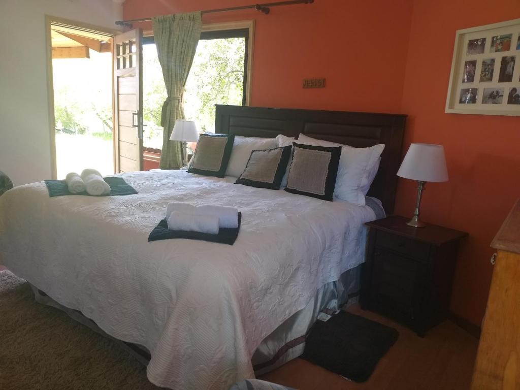 1 dormitorio con 1 cama grande con sábanas y almohadas blancas en Hospedaje el juncal, en Puerto Ingeniero Ibáñez