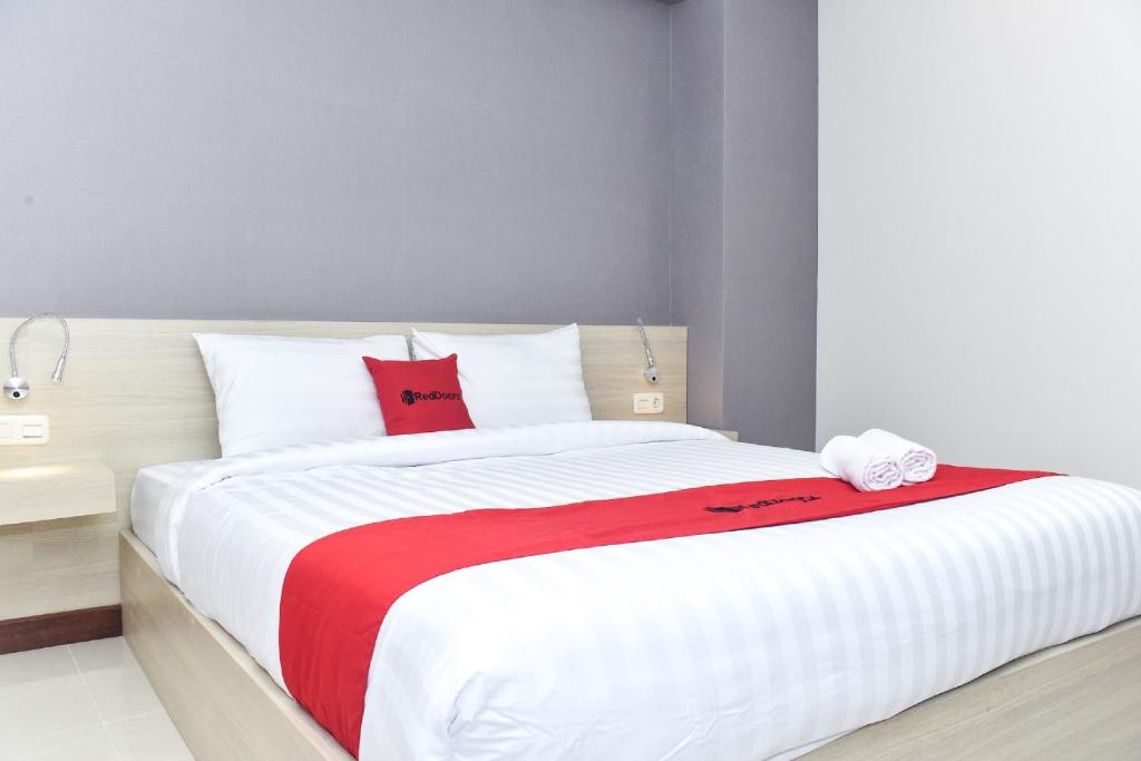 a bedroom with a large white bed with red pillows at RedDoorz near Stasiun TVRI Surabaya 2 in Dukuhkupang