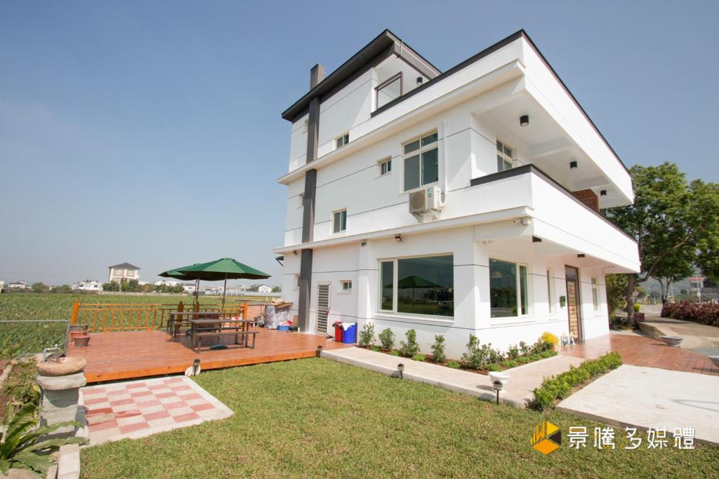 a white house with a patio and a yard at Tong Xin Farmstay in Gongguan