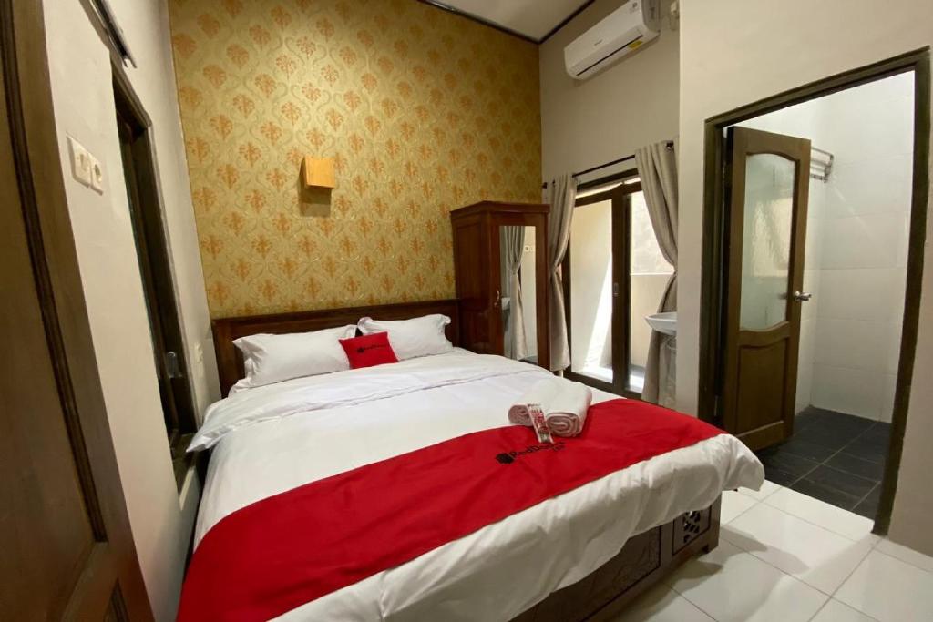 una camera da letto con un grande letto con una coperta rossa di RedDoorz near Mojokerto Train Station 