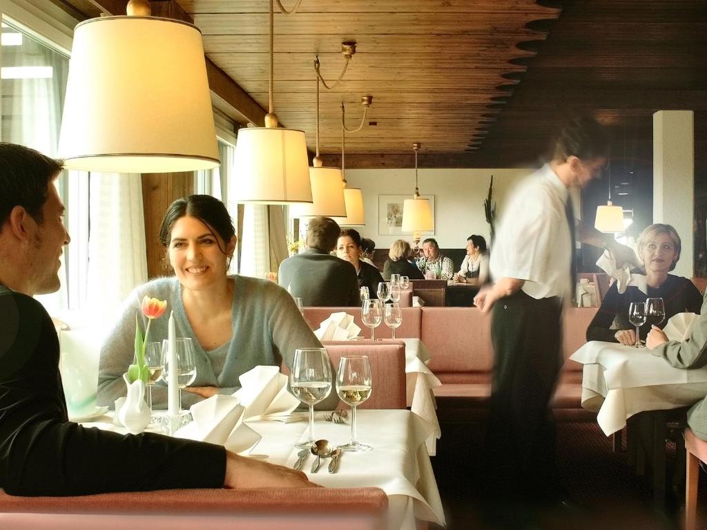 a woman sitting at a table in a restaurant at Wellnesshotel Linde in Sulzberg