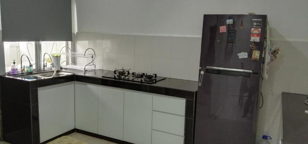a kitchen with a black refrigerator and a sink at Maryam kiara kerteh homestay in Kertih