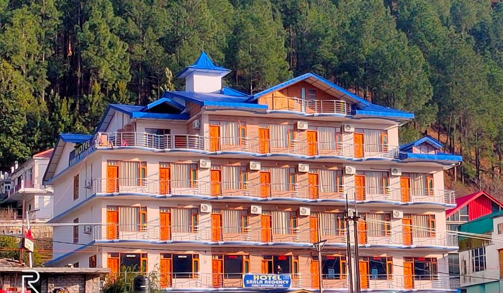 un grand bâtiment avec un toit orange et bleu dans l'établissement Hotel Sarla Regency, à Kulu
