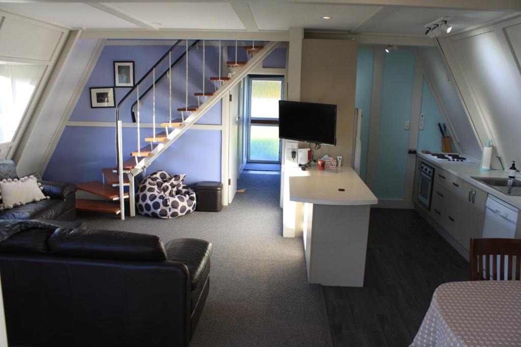 ein Wohnzimmer mit einer Treppe und einer Couch in der Unterkunft Classic A-frame on Milford in Te Anau