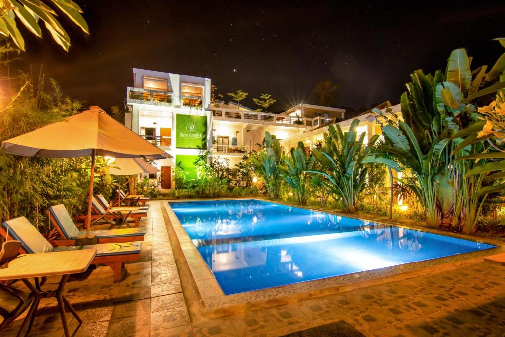 Diva Lombok Resort في سينغيغي: مسبح في الليل مع طاولة وكراسي