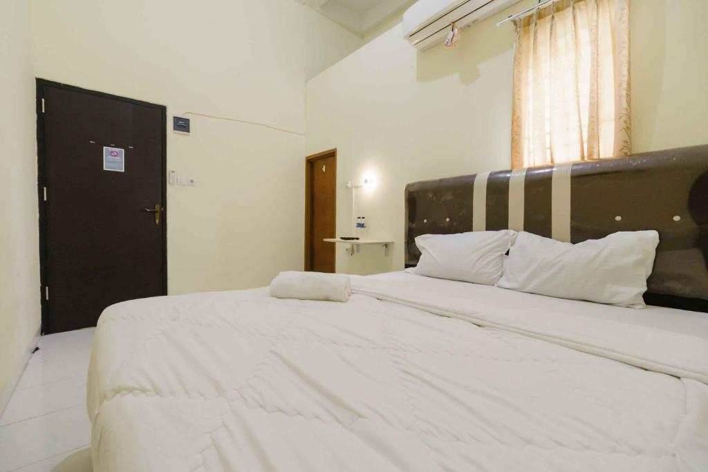ein Schlafzimmer mit einem großen Bett mit weißer Bettwäsche und Kissen in der Unterkunft RedDoorz near OPI Mall Palembang 2 in Palembang