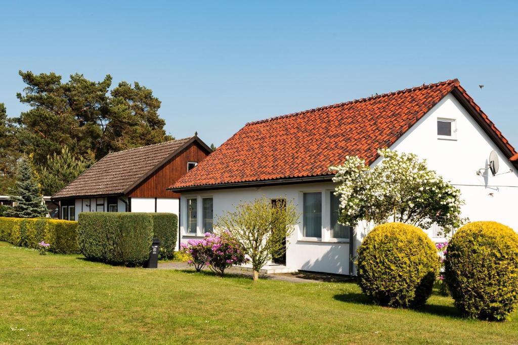 ein weißes Haus mit rotem Dach und Büschen in der Unterkunft Holiday home Fuhlendorf 1 in Fuhlendorf